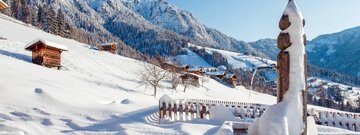 Im Vordergrund ein völlig verschneiter Brunnen, im Hintergrund die einzigartigen Häuser im Alpbacher Baustil