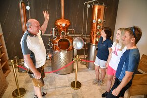 Ein Herr zeigt drei weiteren Personen stolz seine Schnapsbrenn Maschine beim Pinzgerhof. | © Alpbachtal Tourismus | Grießenböck