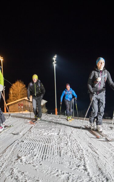 Ski touring in the evening Going on an evening ski tour on the illuminated piste