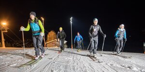 Skitouren am Abend Eine abendliche Skitour auf der beleuchteten Piste unternehmen